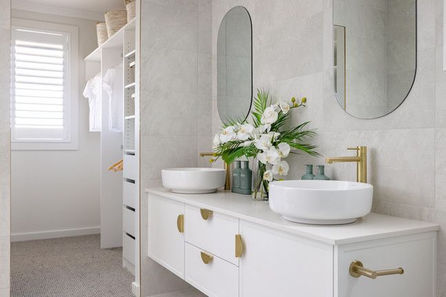 A bathroom with two sinks , two mirrors and a walk in closet.
