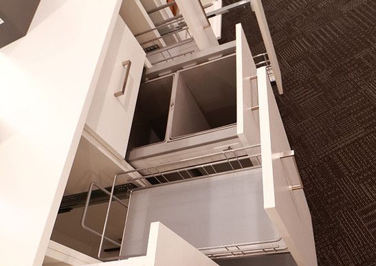 A kitchen with drawers open and a trash can in the middle.