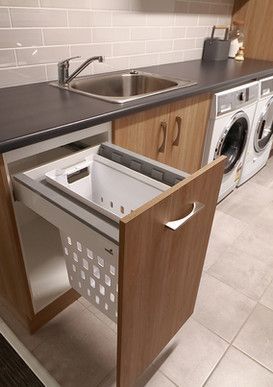 A laundry room with a sink, washer and dryer, and a laundry basket.