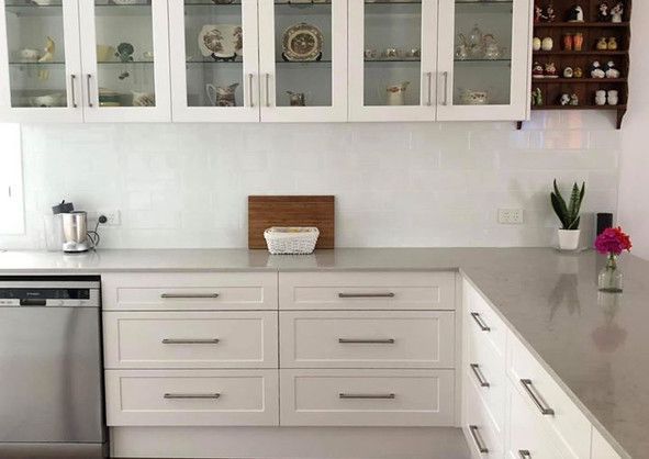 A kitchen with white cabinets and a stainless steel dishwasher.