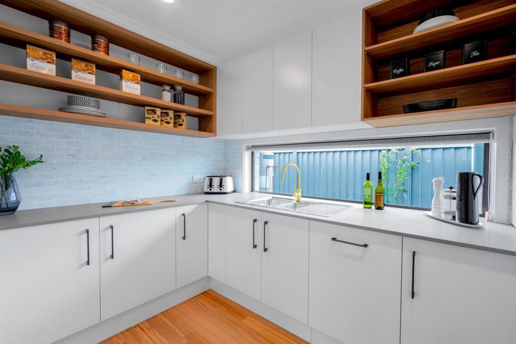 A kitchen with white cabinets, wooden counter tops, stainless steel appliances and a sink.