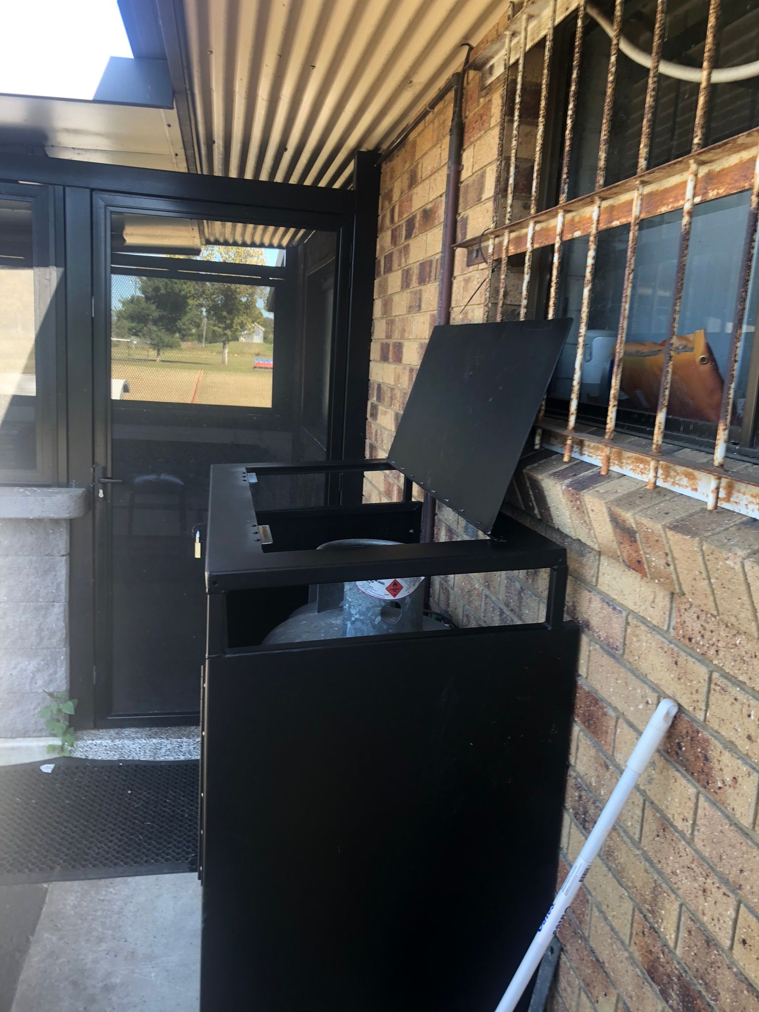 Black Metal Trash Bin With Open Lid Next To A Building Entrance — Soward Steel & Aluminium Fabrication in South Lismore, NSW