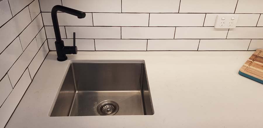 kitchen sink with white tile backsplash