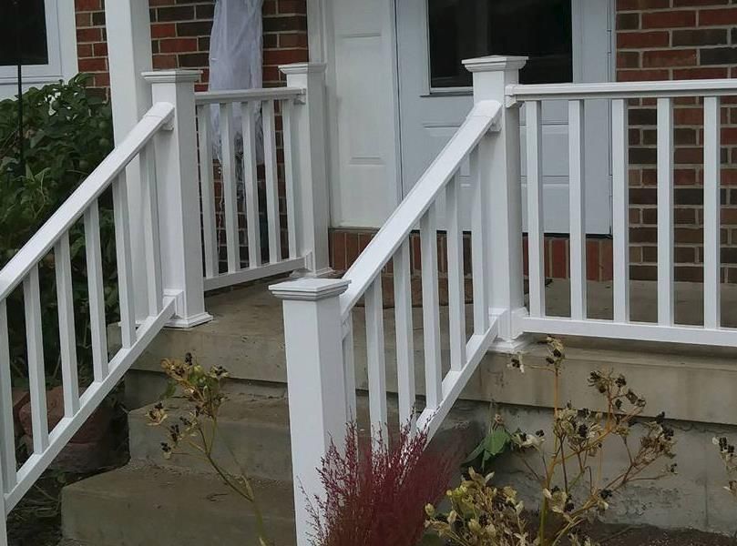 A wooden fence surrounds a lush green yard in front of a house.