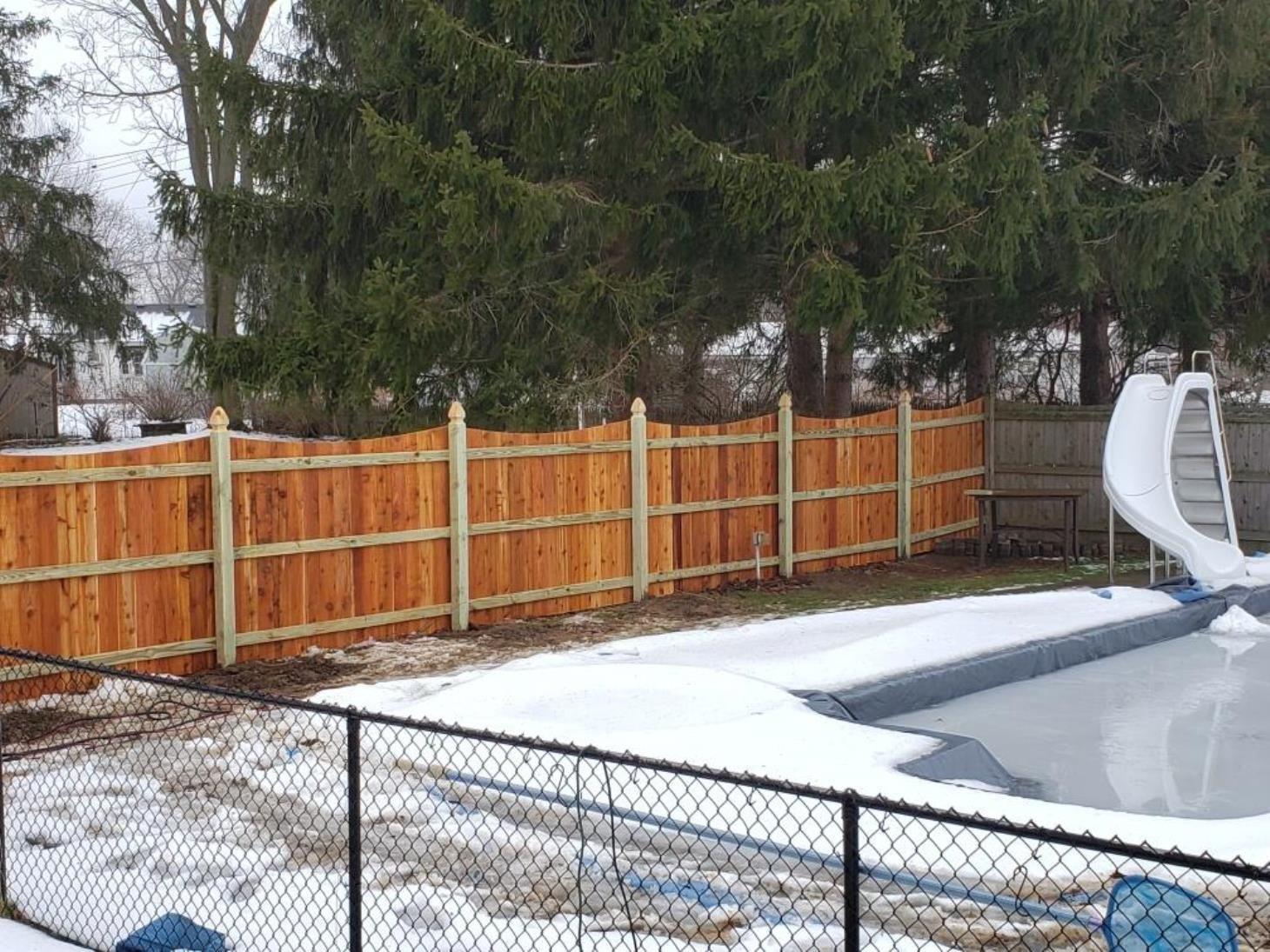 A chain link fence surrounds a park with a building in the background
