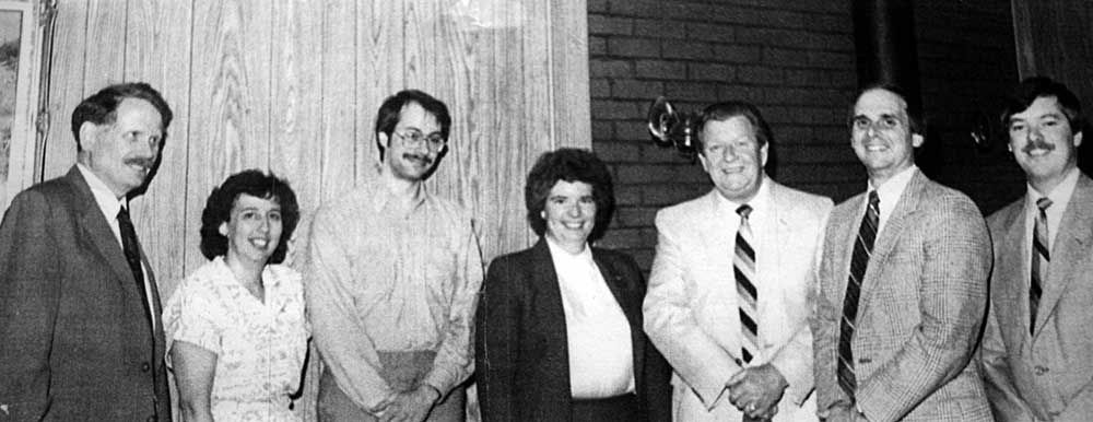 A group of people standing next to each other in front of a brick wall.