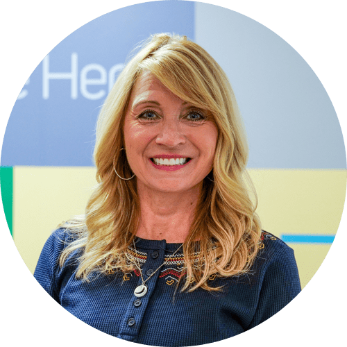 A woman in a blue shirt is smiling in a circle.