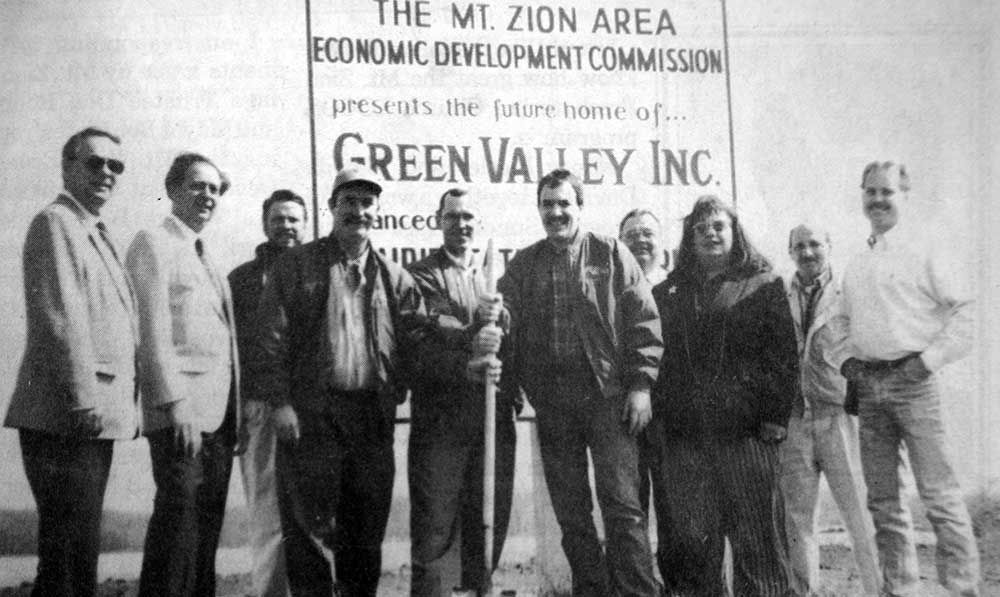 A group of people standing in front of a sign that says green valley inc.