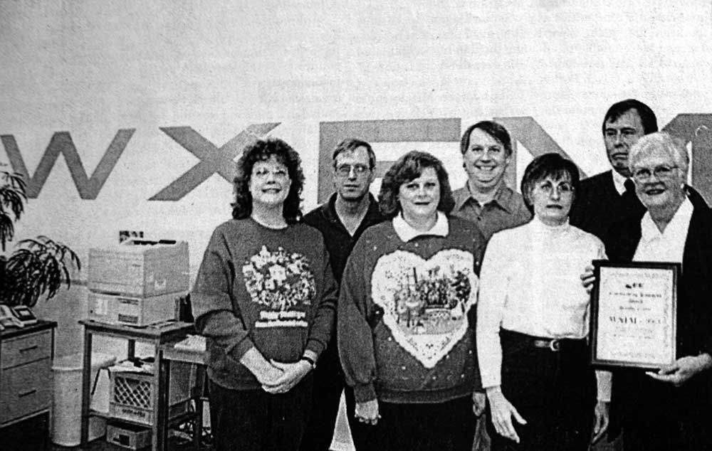 A group of people standing in front of a wall that says wx