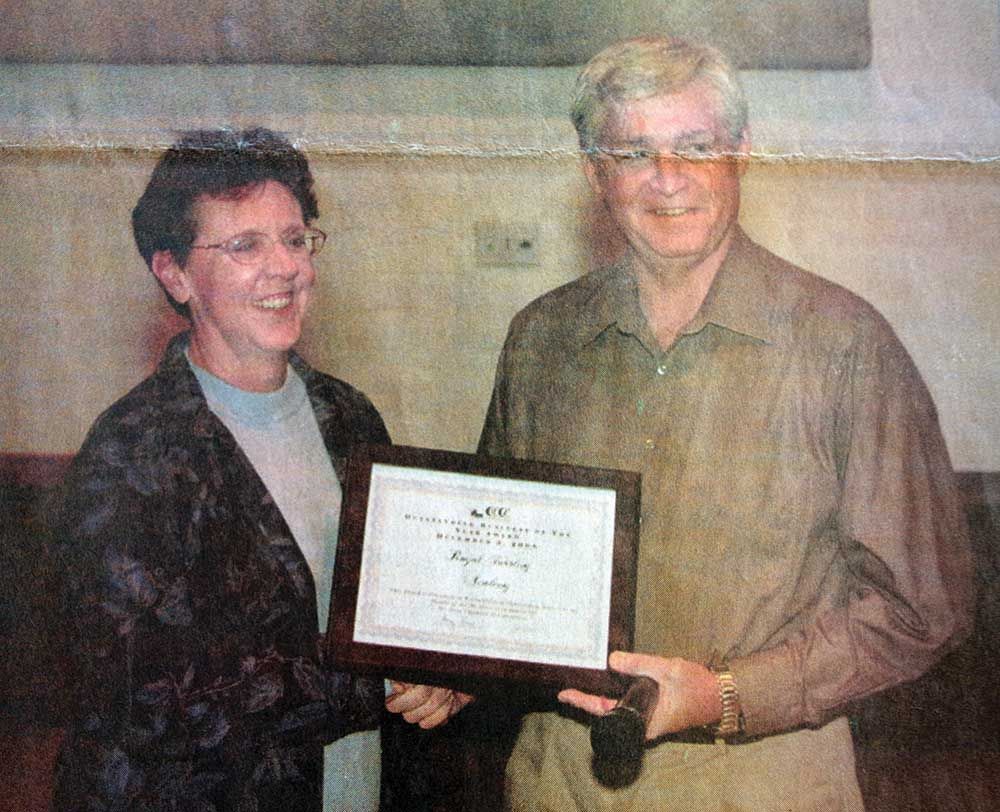 A man and a woman are holding a framed certificate