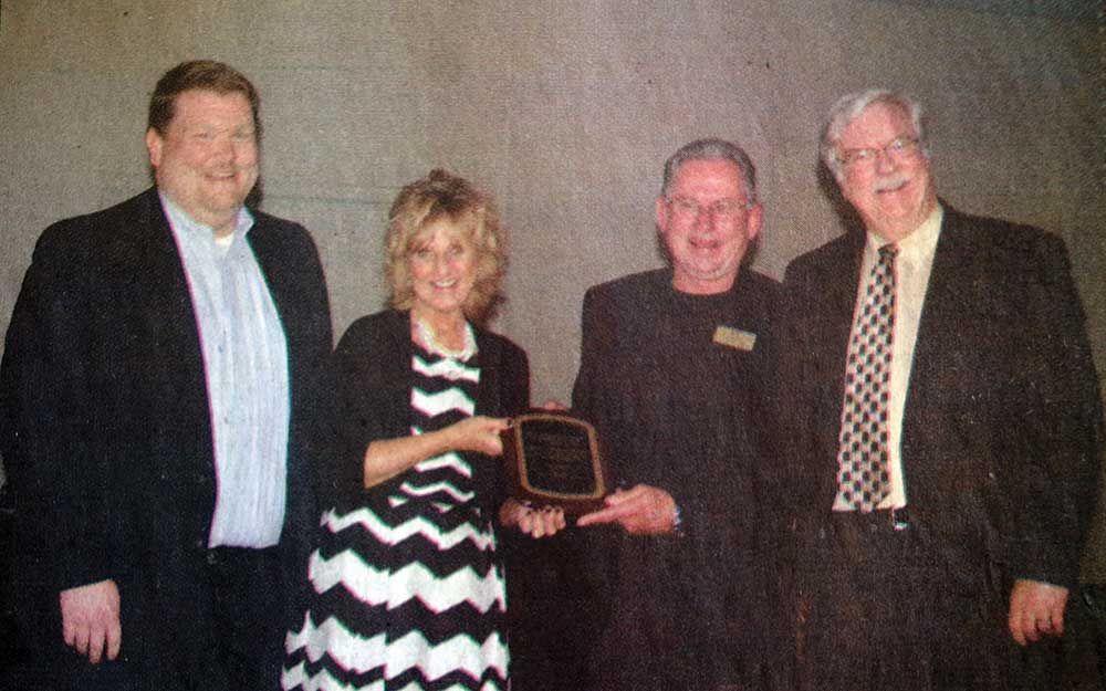 A group of people standing next to each other holding a plaque.