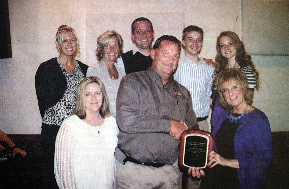 A group of people standing around a man holding a plaque