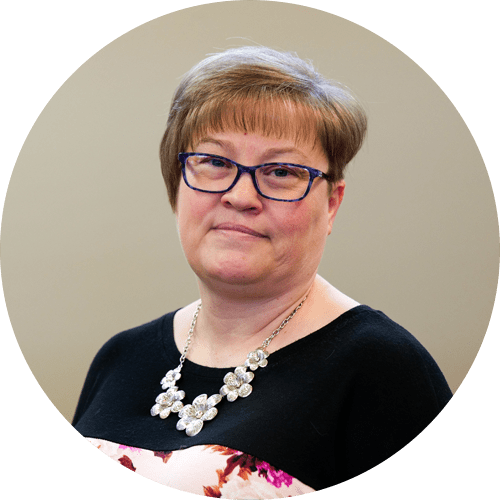 A woman wearing glasses and a necklace is in a circle.