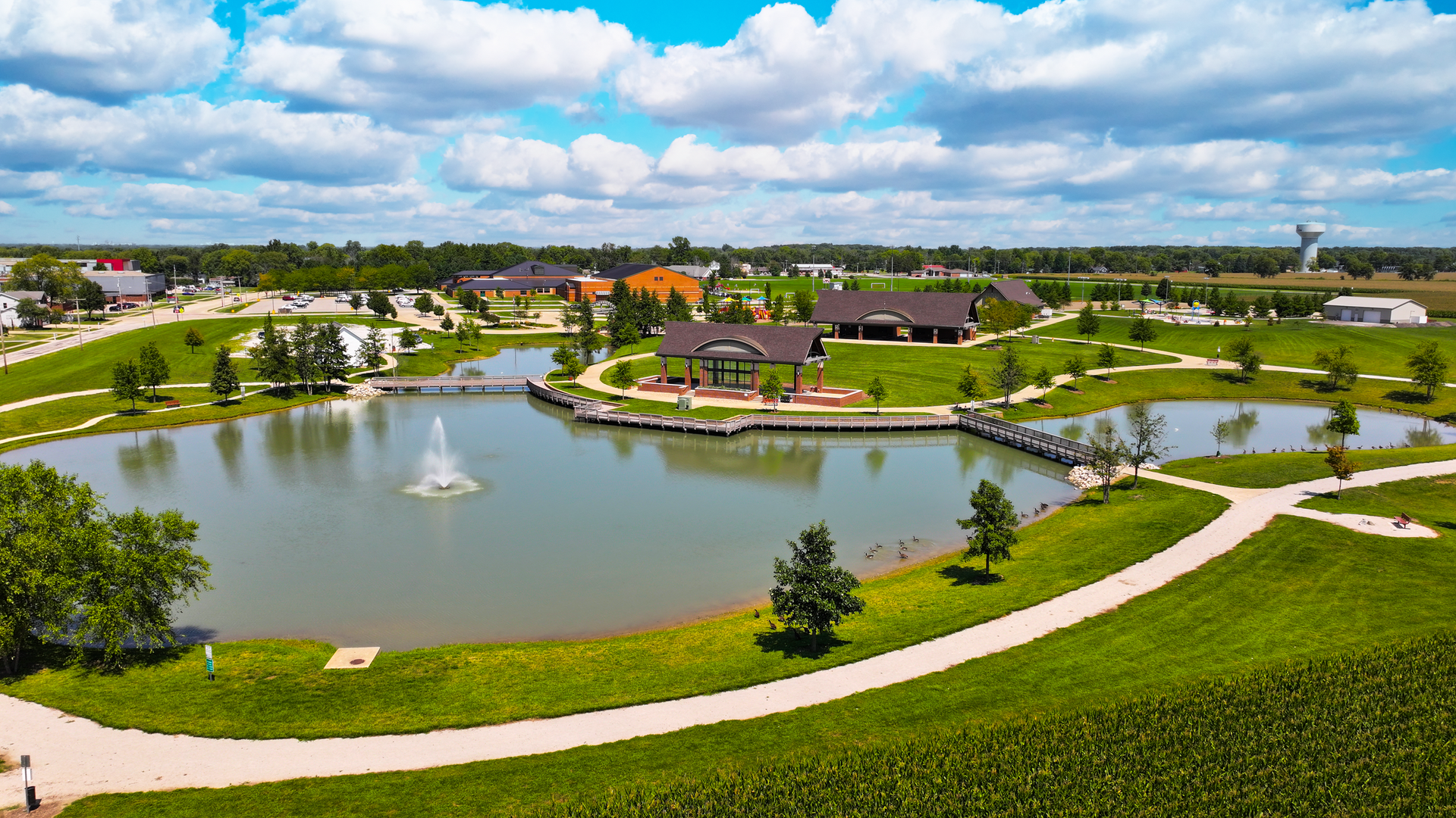 An aerial view of a park with a pond and a fountain.