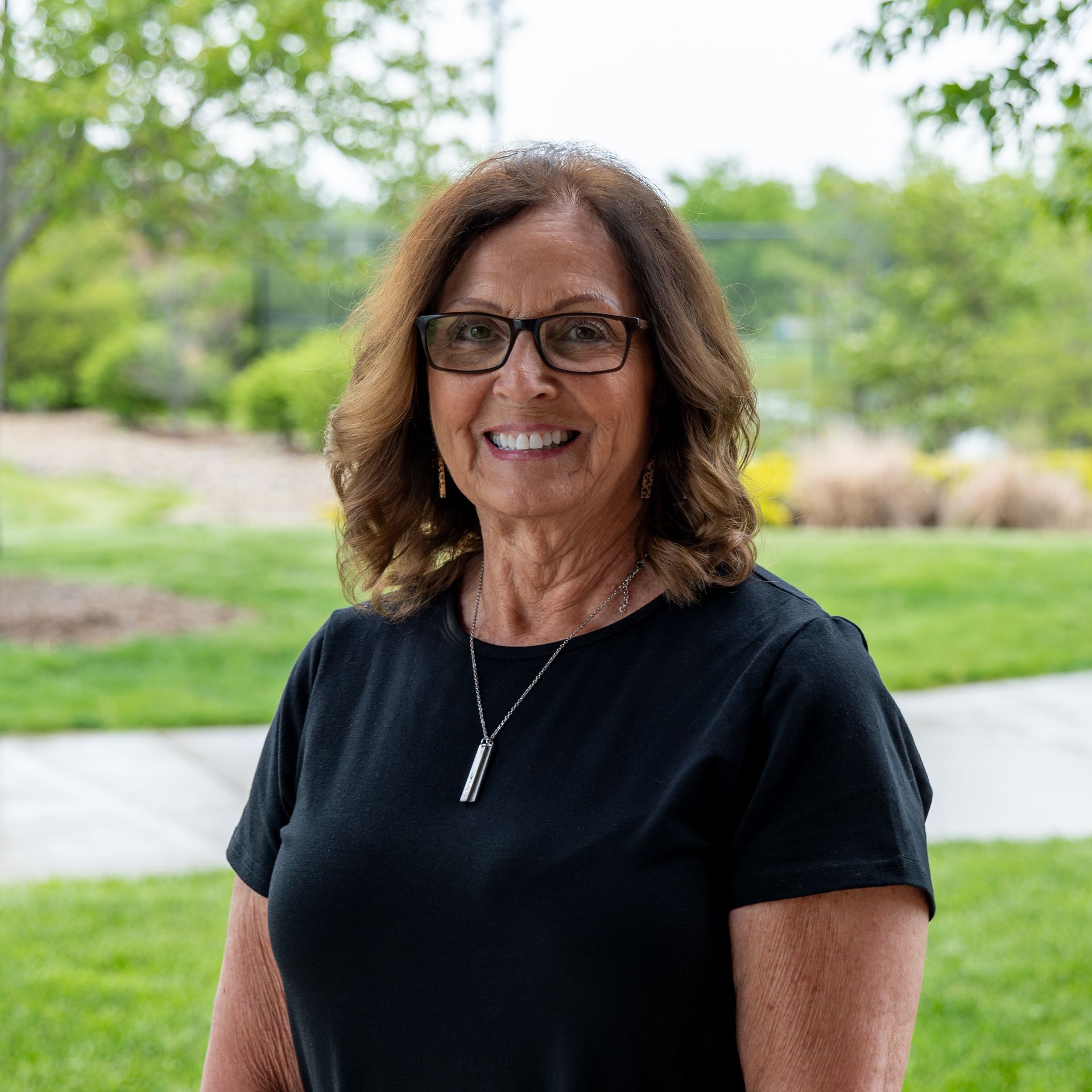 A woman wearing glasses and a black shirt is smiling for the camera.