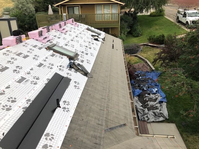 Roof partially under construction with insulation, skylights, and black flashing.