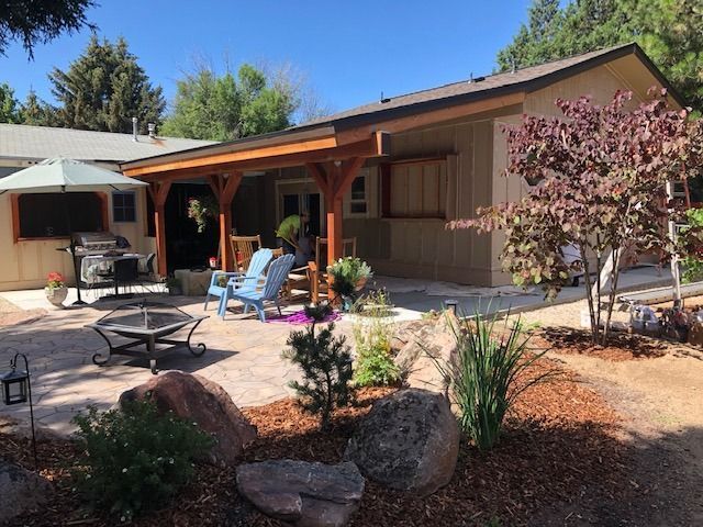 Patio with stone pavers, wooden pergola, and landscaped garden.