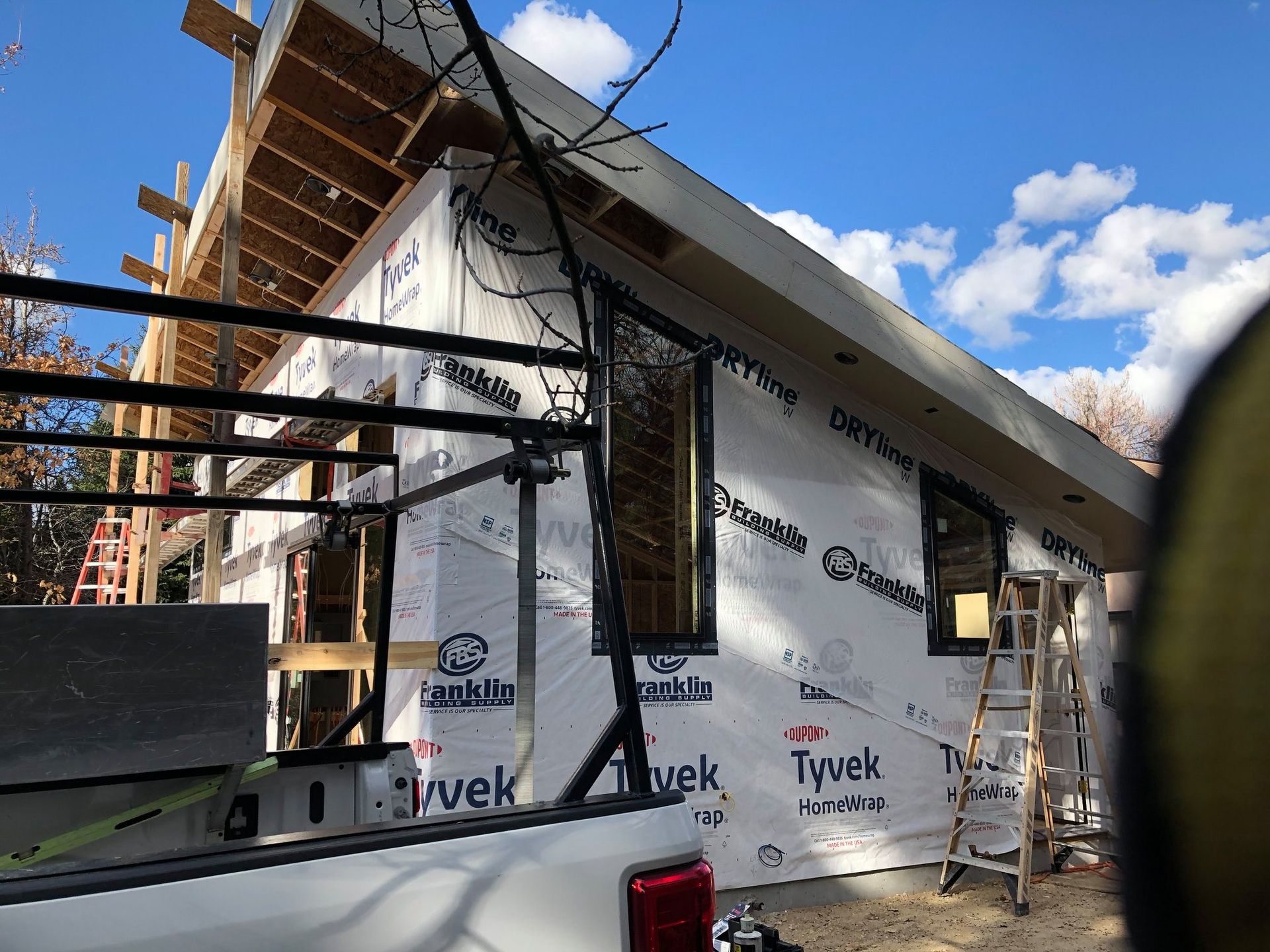 Construction site with a partially built house wrapped in Tyvek.