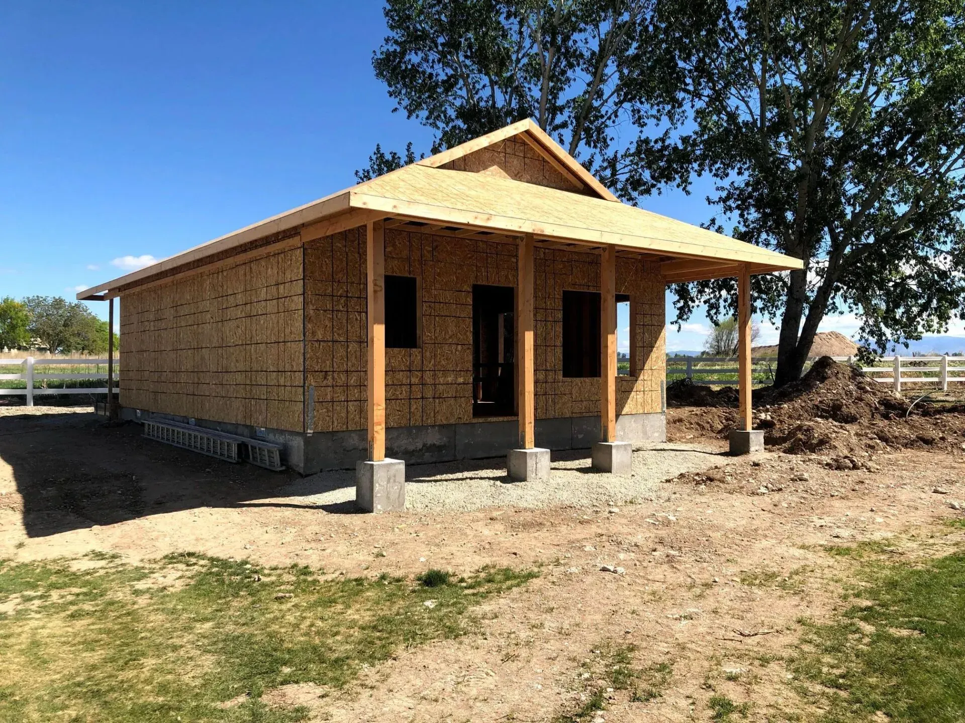 Construction of a small, wooden building with a porch and gable roof on a sunny day.