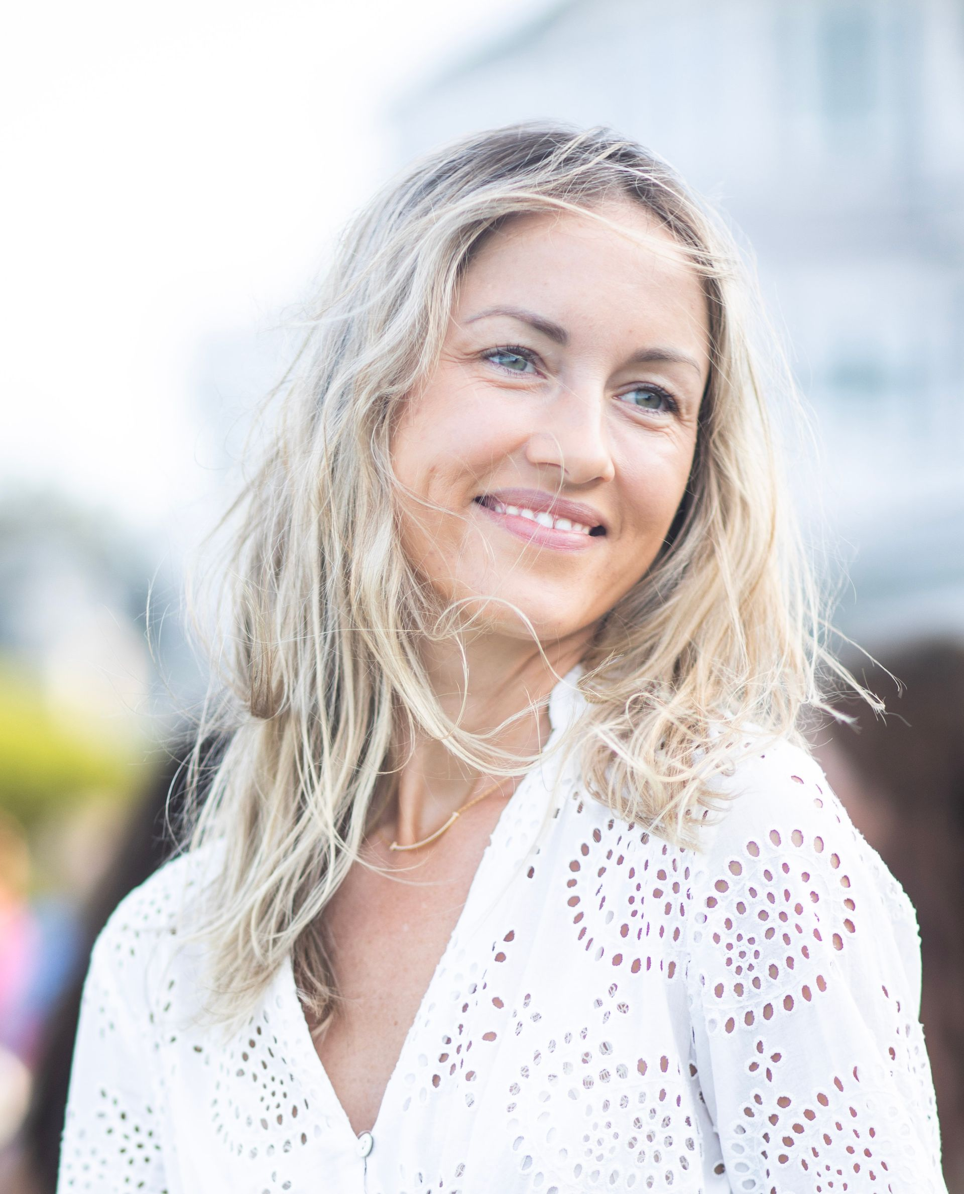 A woman is sitting at a desk with a laptop and a vase of flowers.
