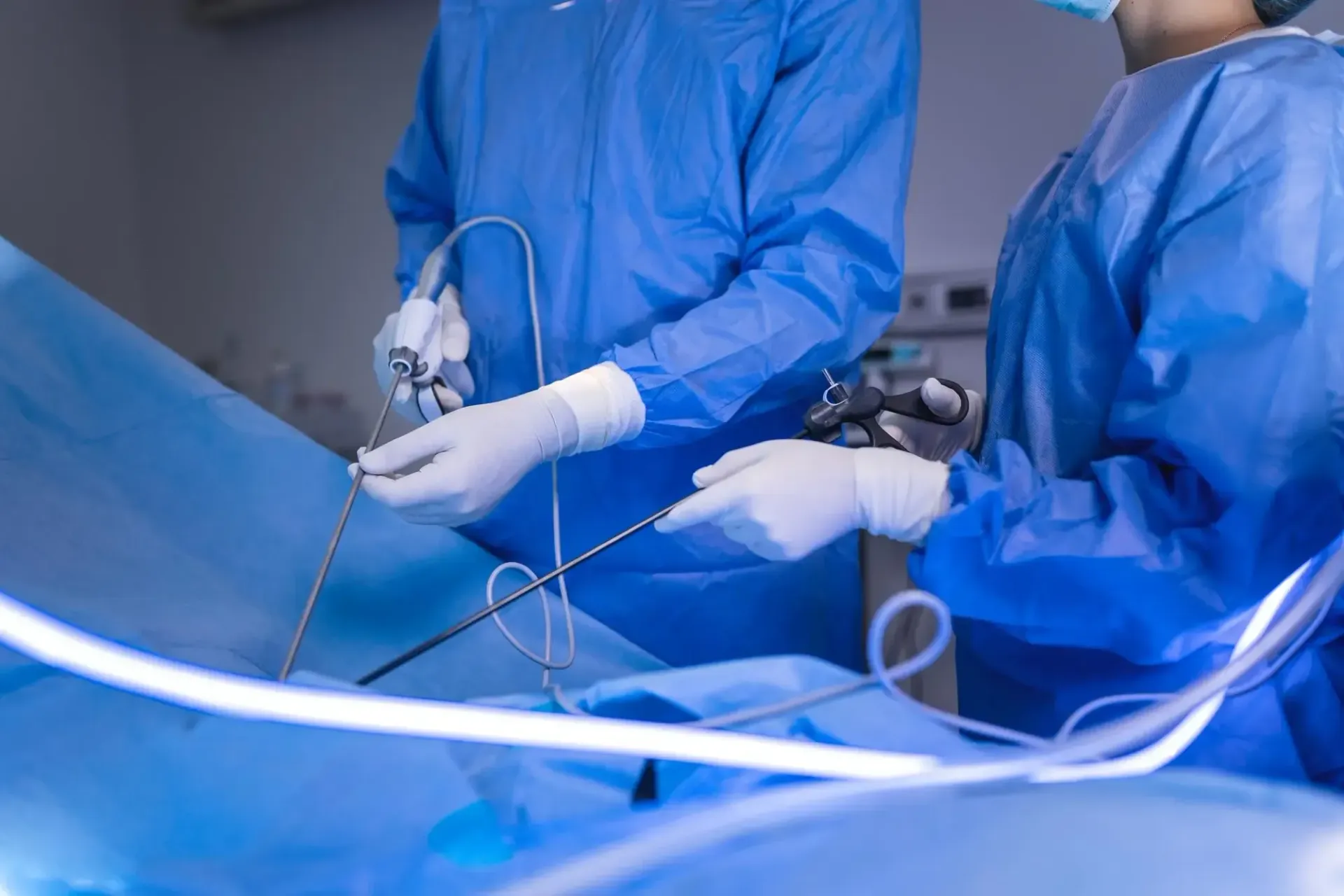 Dois cirurgiões estão realizando uma cirurgia laparoscópica em um paciente em uma sala de cirurgia.
