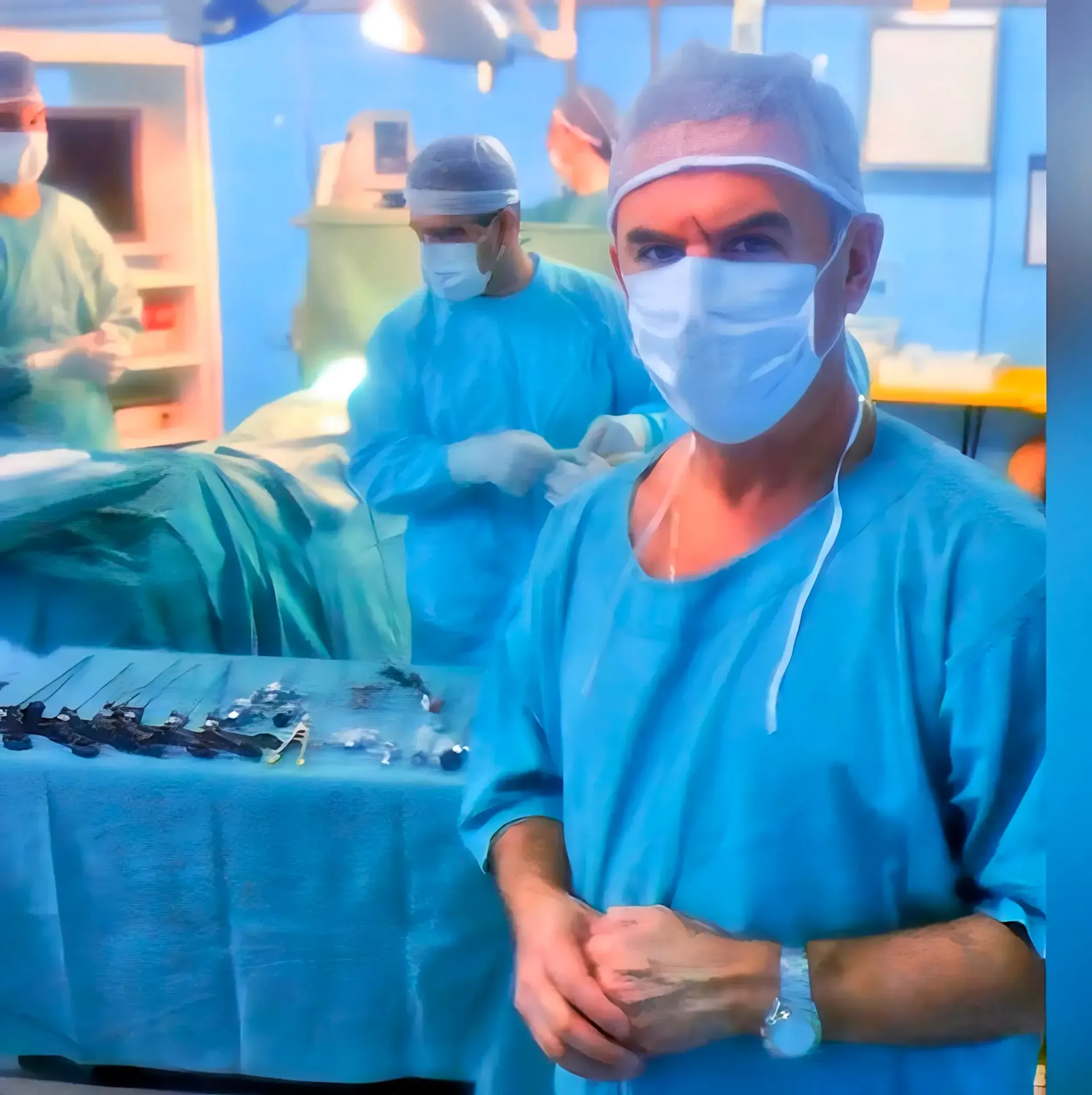 Um médico sorridente com um estetoscópio pendurado no pescoço está de pé com os braços cruzados.