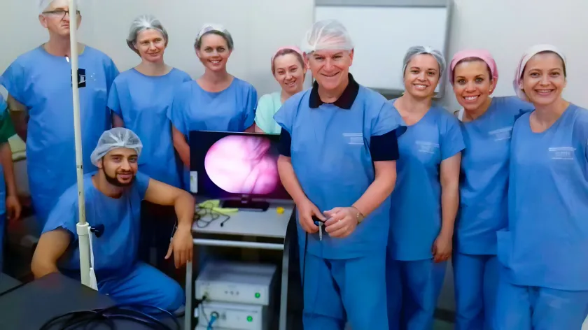 Um cirurgião está sentado em uma sala de cirurgia com os braços cruzados.