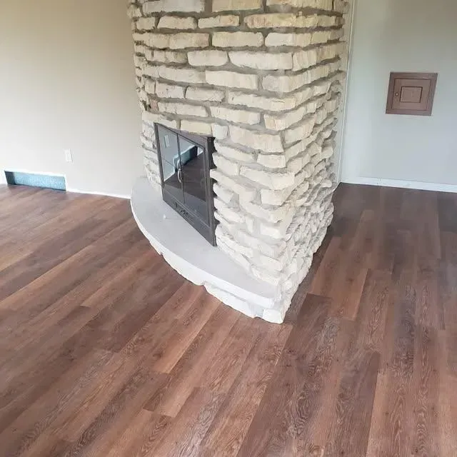 Fireplace with stone exterior and wooden flooring in a room.