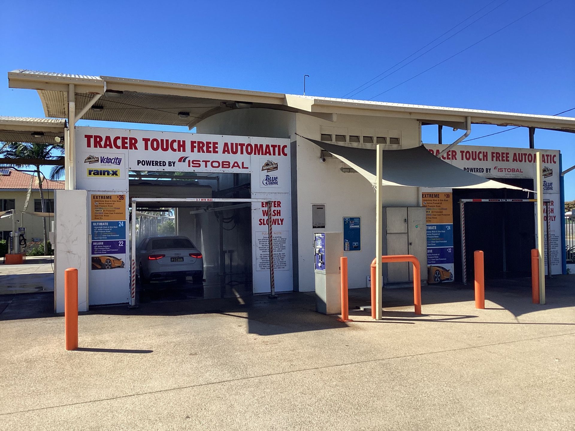 A car entering a Tracer touch-free automatic car wash with blue and white structures and a sunny sky.— Whitsunday Wash In Bowen, QLD