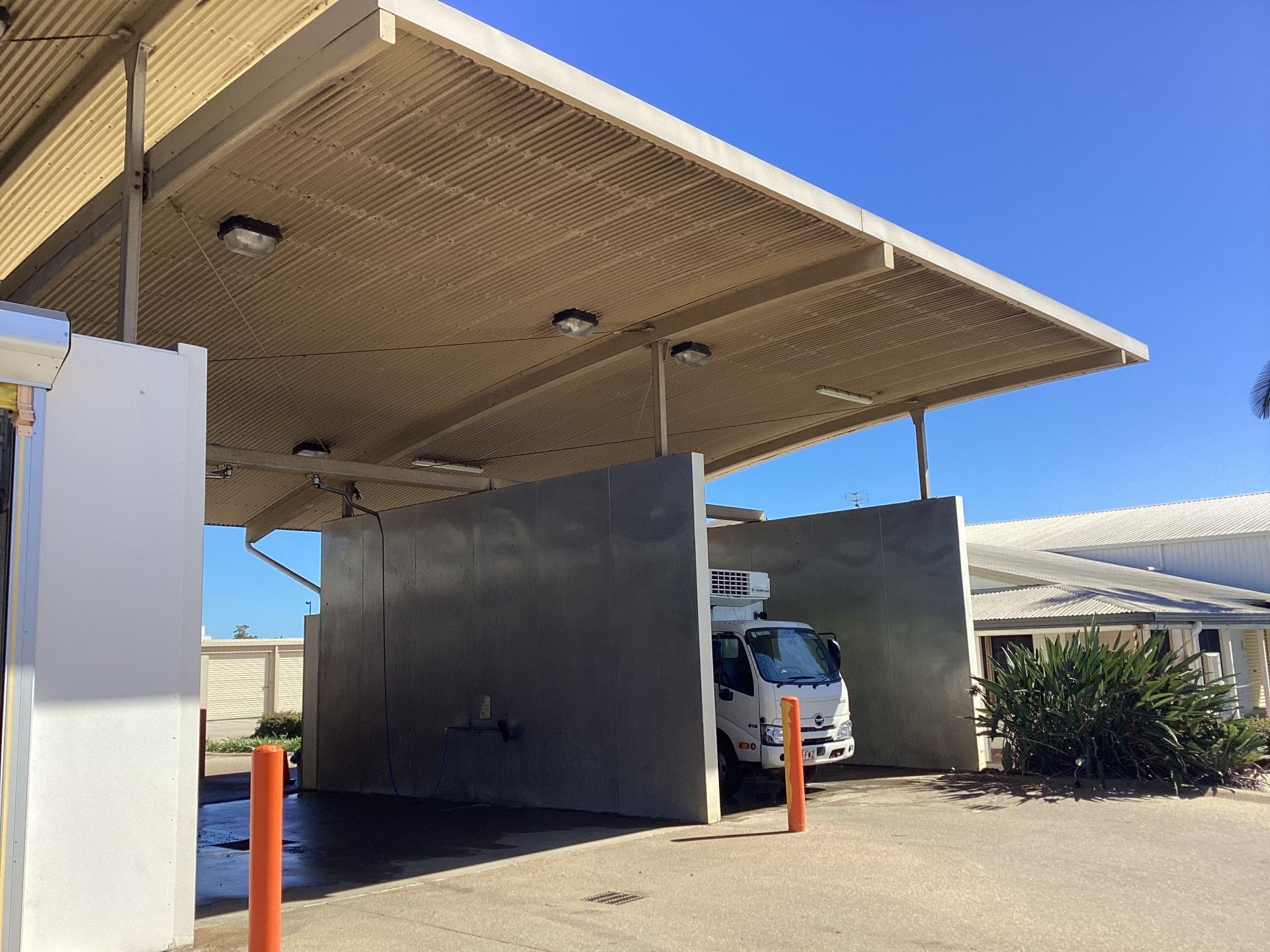 White truck parked in a car wash bay with gray walls and tan roof, sunny day.— Whitsunday Wash In Bowen, QLD