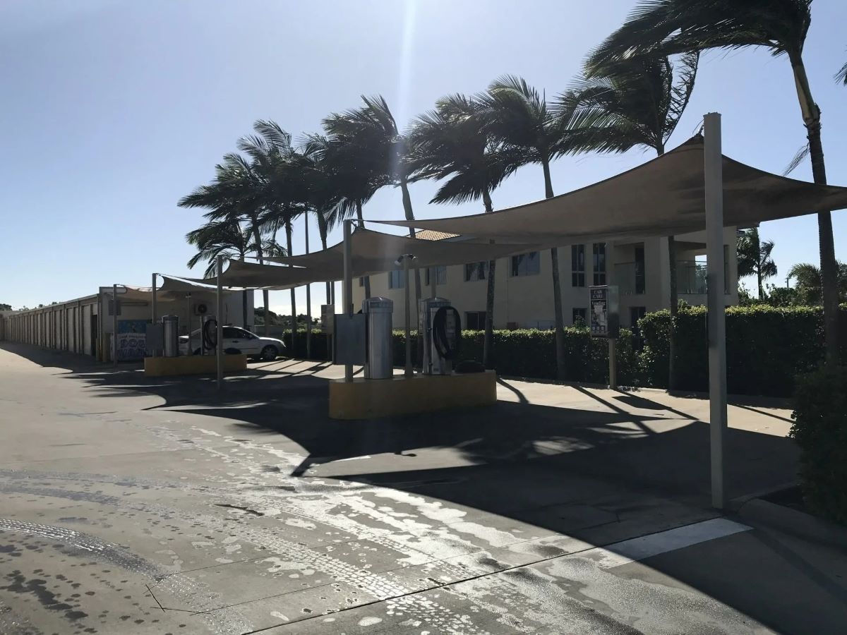 A Parking Lot with A Row of Buildings and Palm Trees — Whitsunday Wash In Bowen, QLD