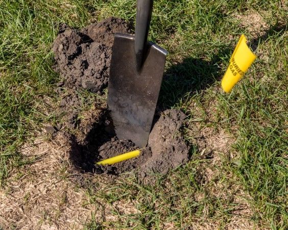 A broken water pipe spews water in a dirt-filled trench.
