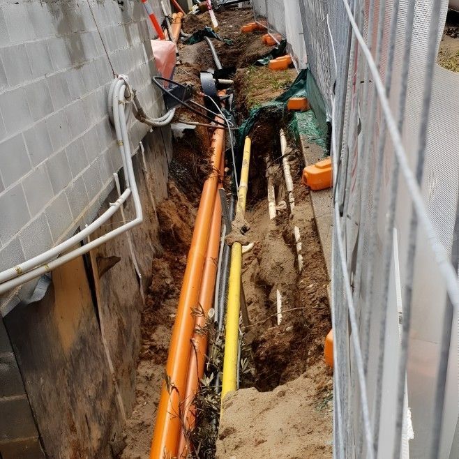 Parking lot with orange traffic cones, curb, and sunlit background of hills and sky.