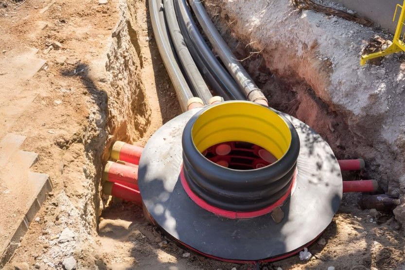 Hand holding a blue utility locator over asphalt, near a yellow line marked with “0.65.”