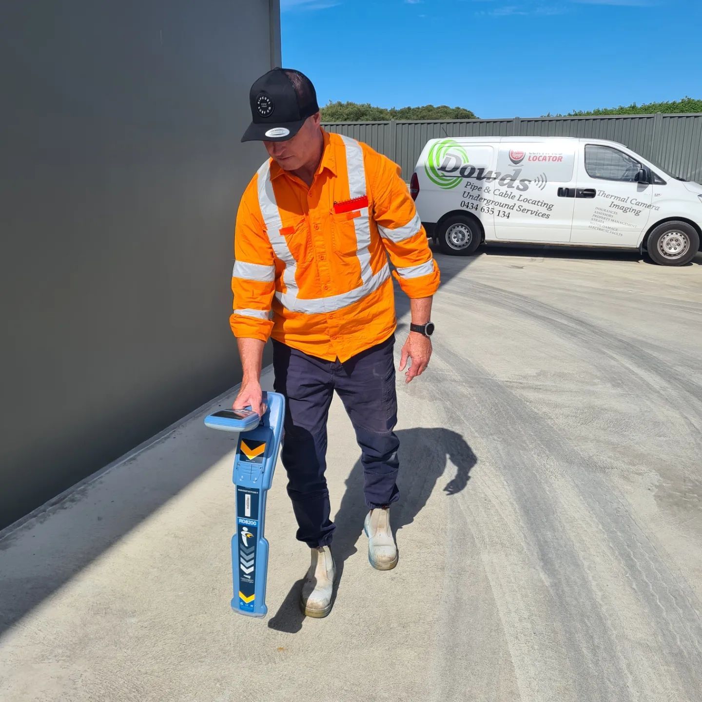 Black pipes and orange wires buried in dark soil.