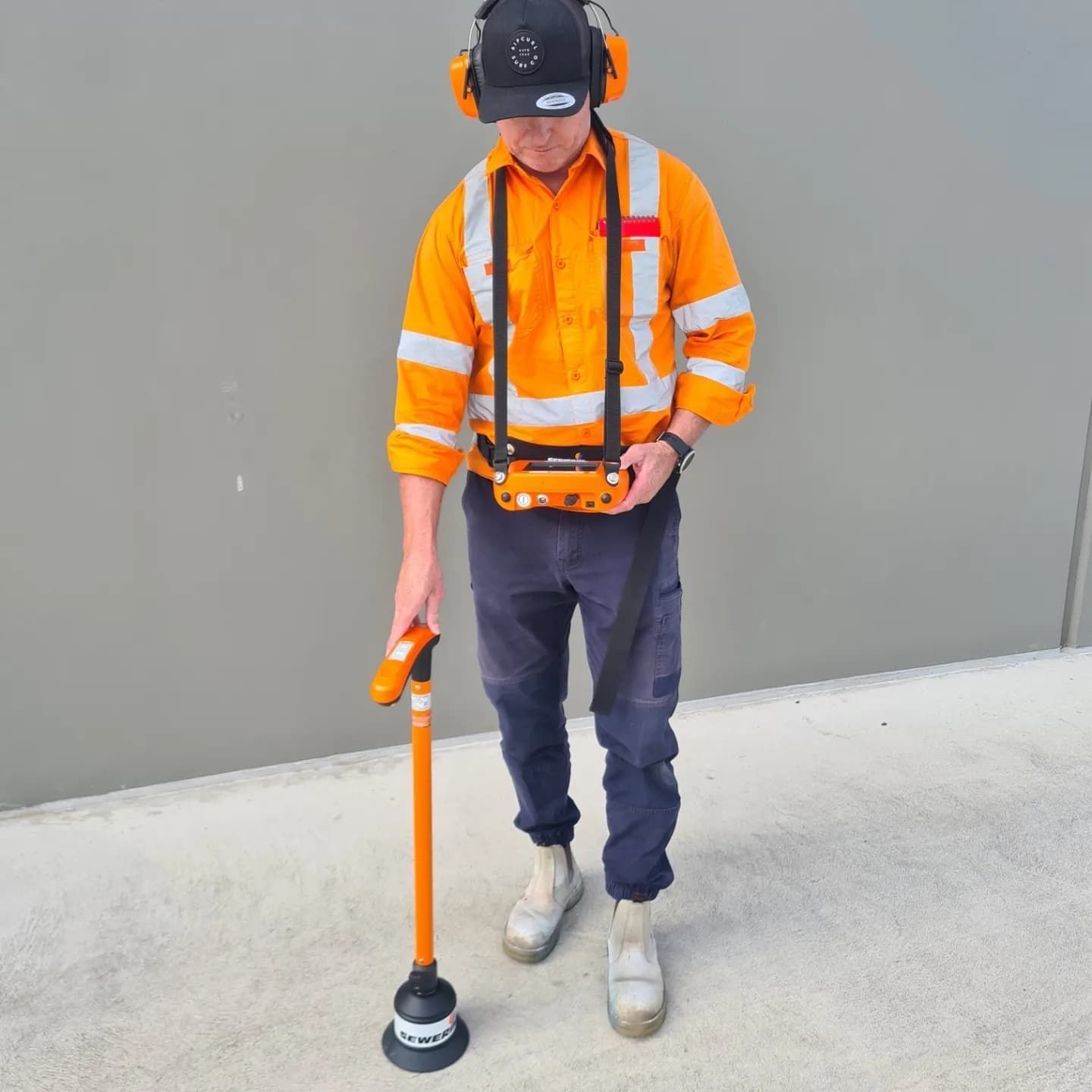 Parking lot with orange traffic cones, curb, and sunlit background of hills and sky.