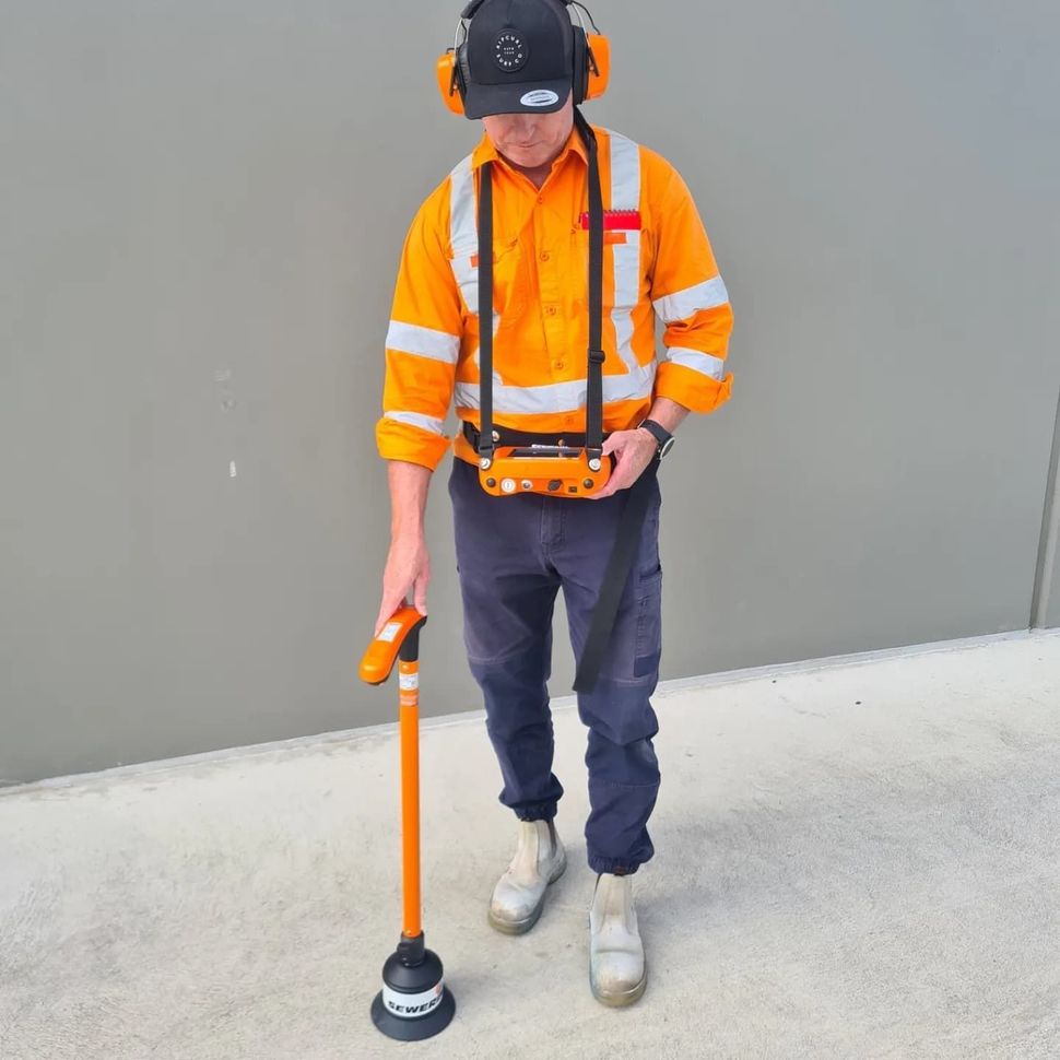 Parking lot with orange traffic cones, curb, and sunlit background of hills and sky.