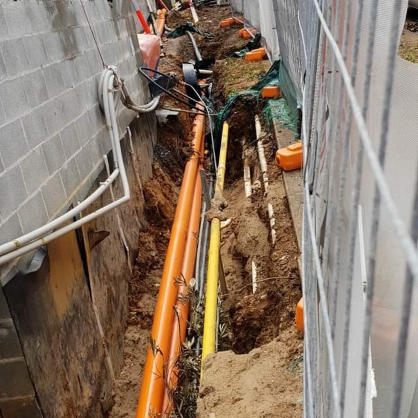 A person uses a utility locator on asphalt next to a curb. Yellow paint indicates a line and the number 0.65.