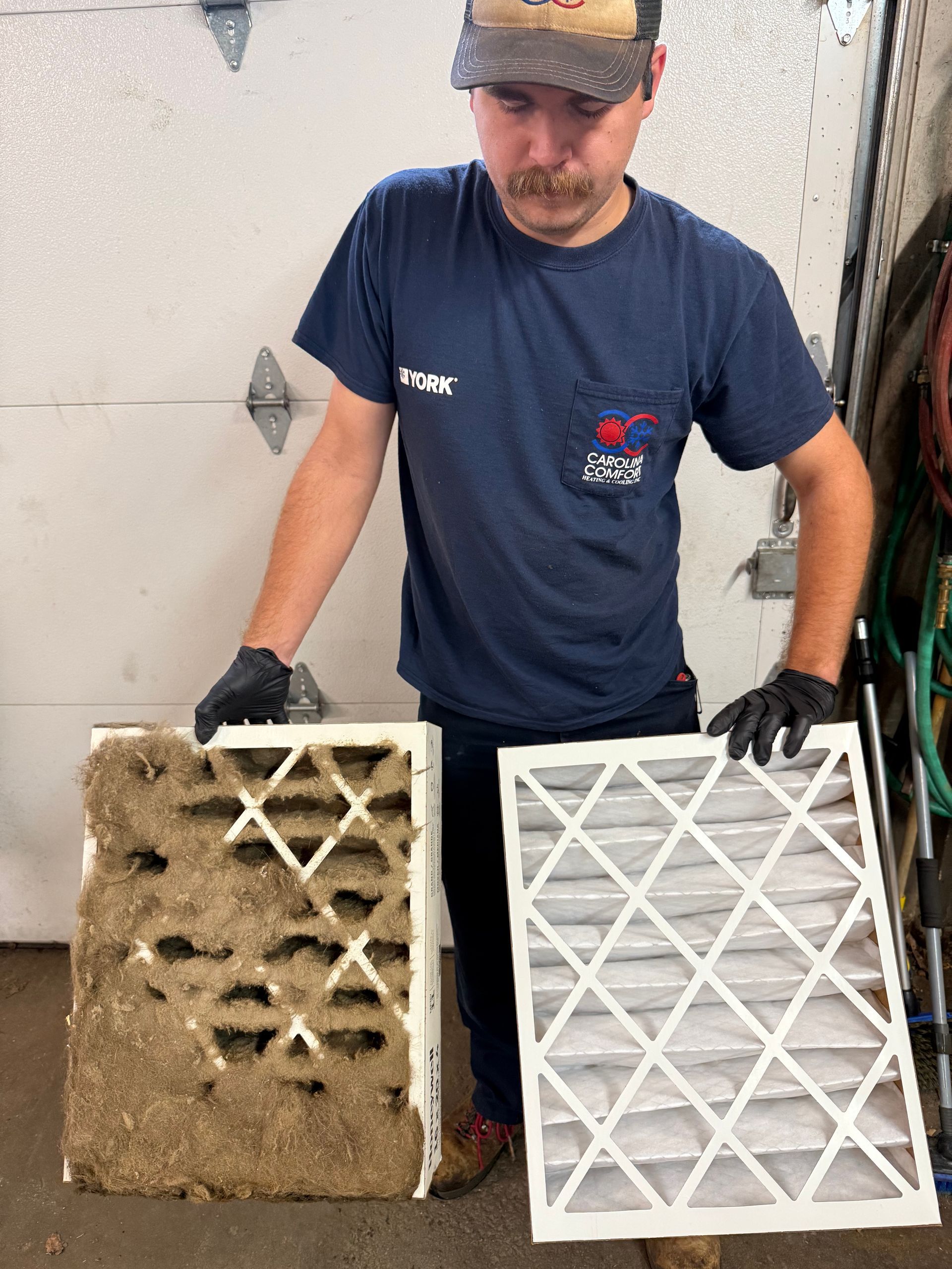 Man holding a dirty and clean air filter, comparing the two. He's wearing a blue shirt and gloves.