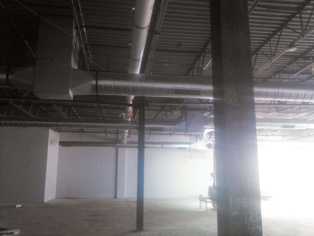 A large empty room with a lot of pipes coming out of the ceiling.