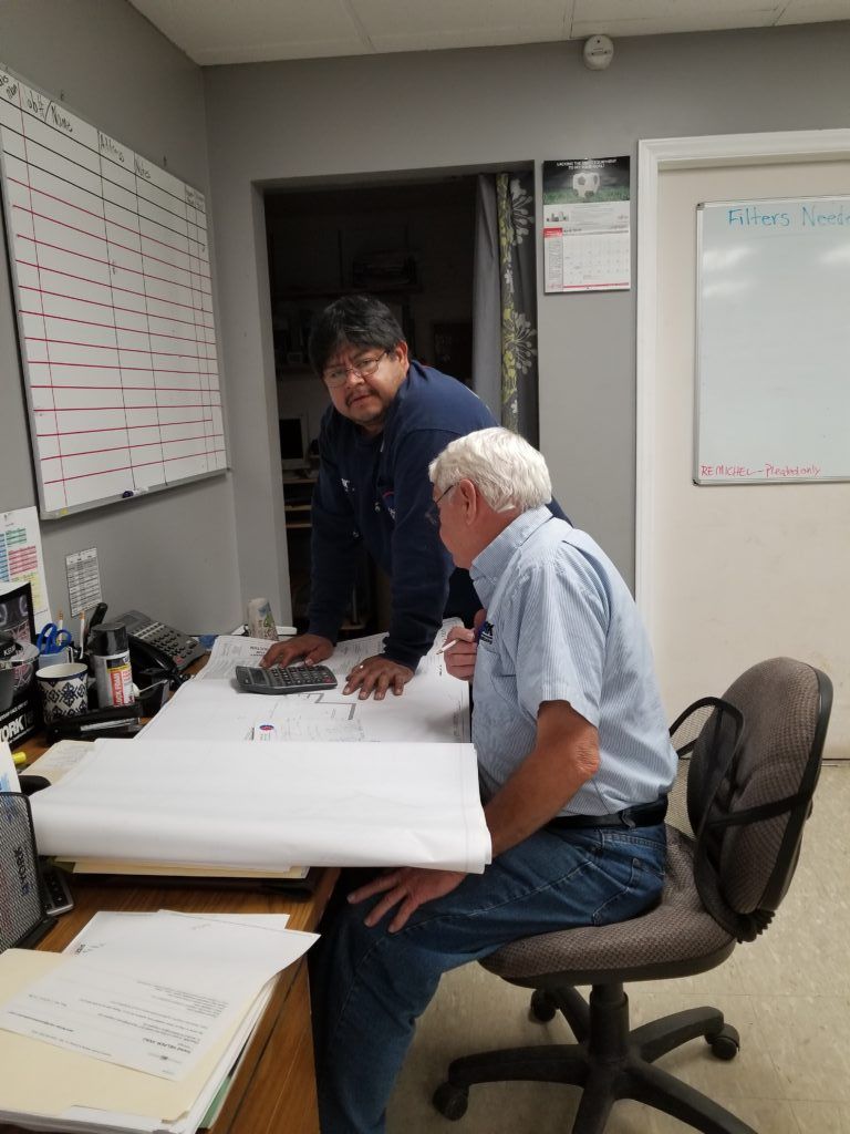Two men are sitting at a desk looking at a piece of paper.