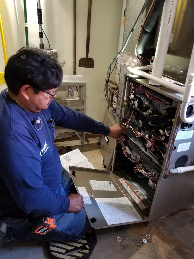 A man is working on an air conditioner in a basement.