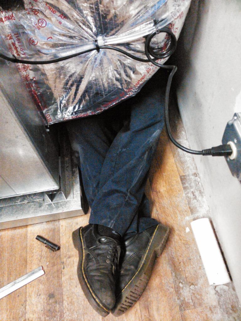 A person is laying on the floor with a bag over their head.