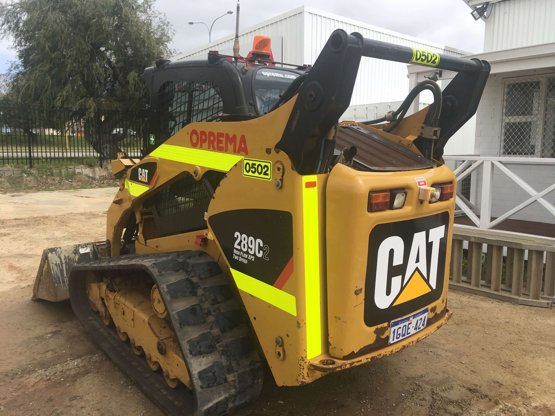 A yellow cat bulldozer is parked in front of a building.