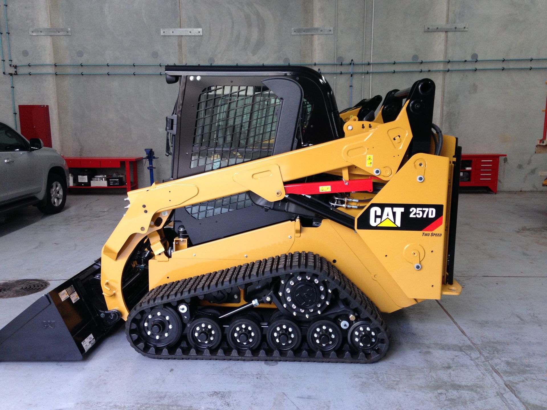 A cat skid steer is parked in a garage