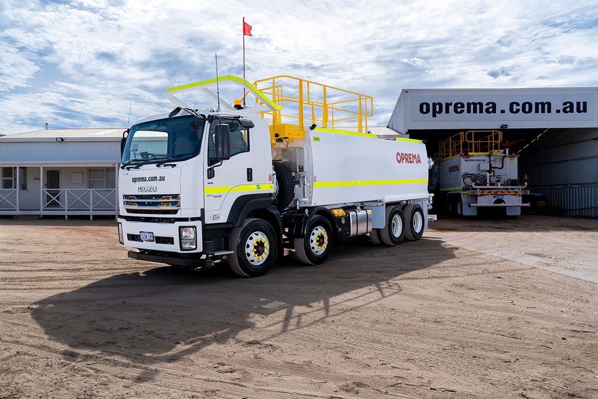 A white and yellow truck is parked in front of a building.