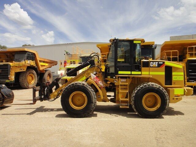 A yellow cat bulldozer is parked next to a dump truck