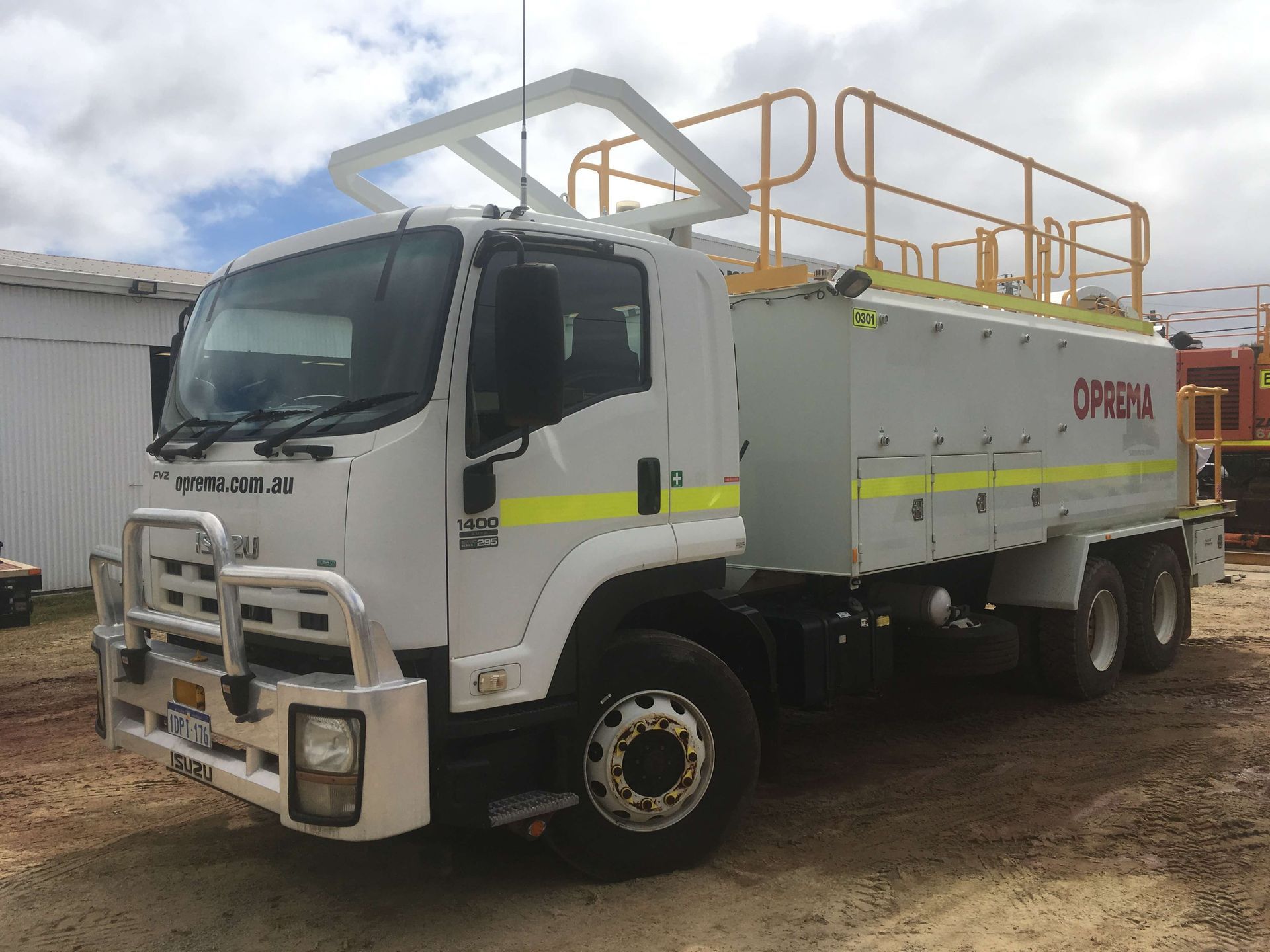 A white truck with a yellow railing is parked in a dirt lot.