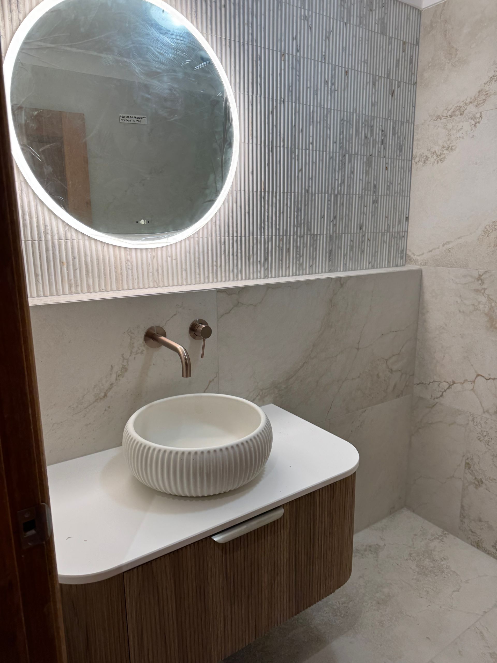 Modern bathroom with a round mirror, vessel sink, and textured walls — Fair Plumbing In Kembla Grange, NSW