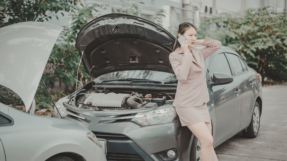 a broken down car with a woman leaning on it